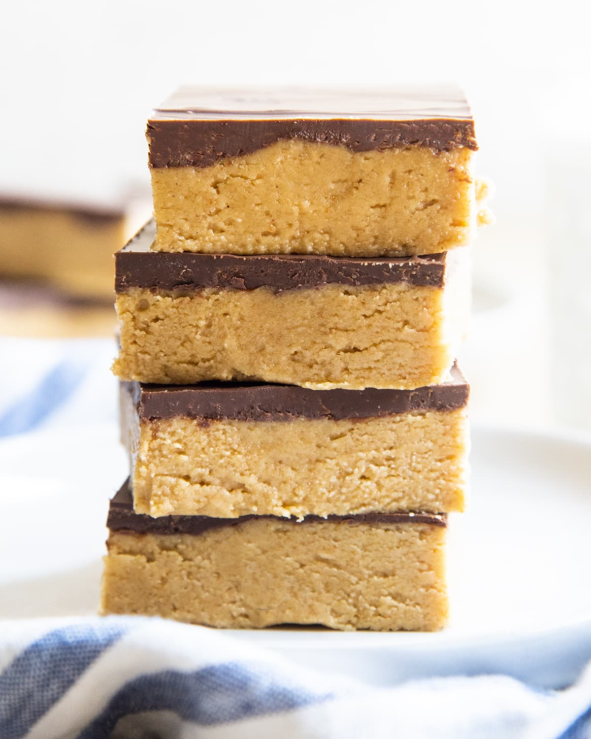 A stack of 4 no bake peanut butter bars topped with a layer of chocolate each.