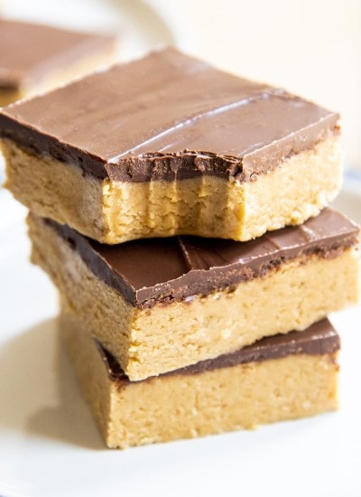 A close up of three no bake chocolate peanut butter bars on a plate, and the top bar has a bite out of it.