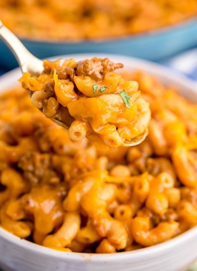 A spoonful of homemade hamburger helper being held above a bowl.