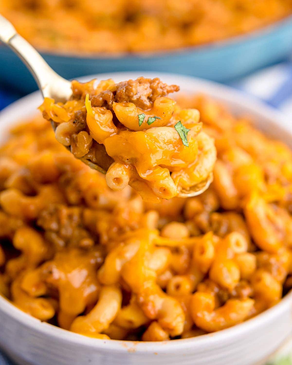 A spoonful of homemade hamburger helper being held above a bowl.