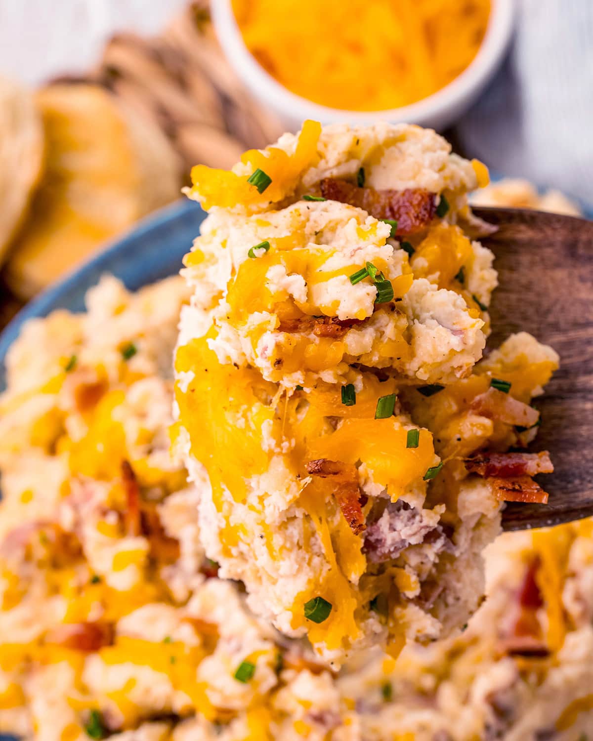 A big spoonful of loaded mashed potatoes covered in cheddar cheese.