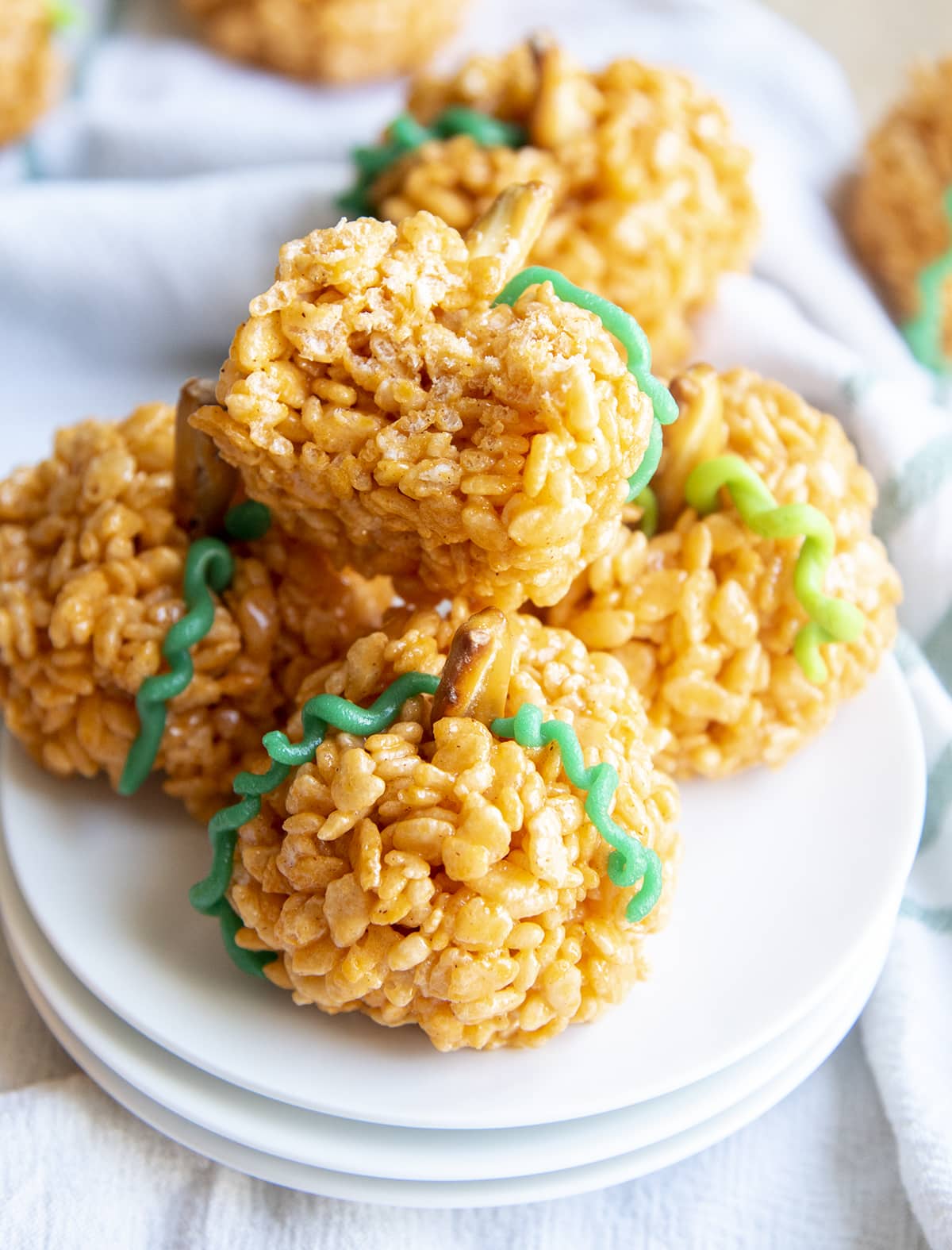 A pile of pumpkin shaped rice krispie treats, and the top one has a bite out of it.