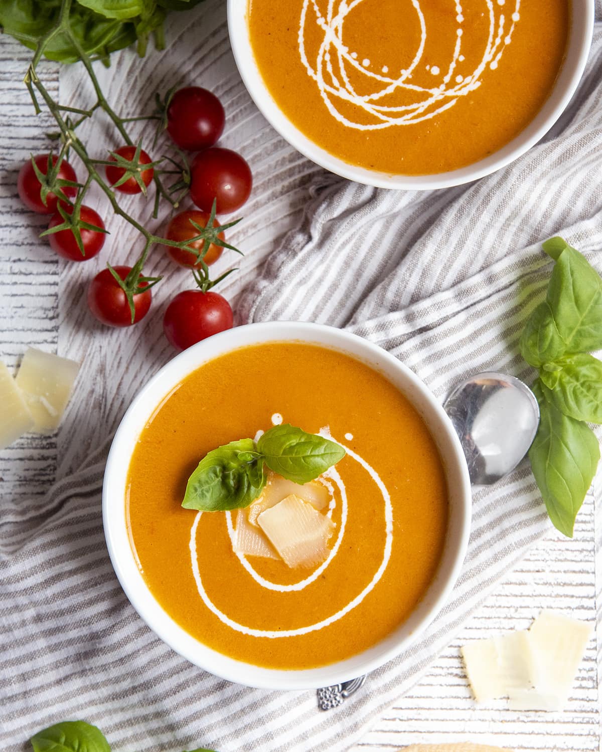 An overhead shot of two bowls of tomato basil soup.