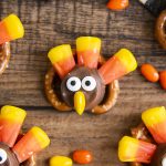 A pretzel topped with a rolo and decorated with candy corn, candy eyes, and a chocolate covered sunflower seed to make it look like a turkey.
