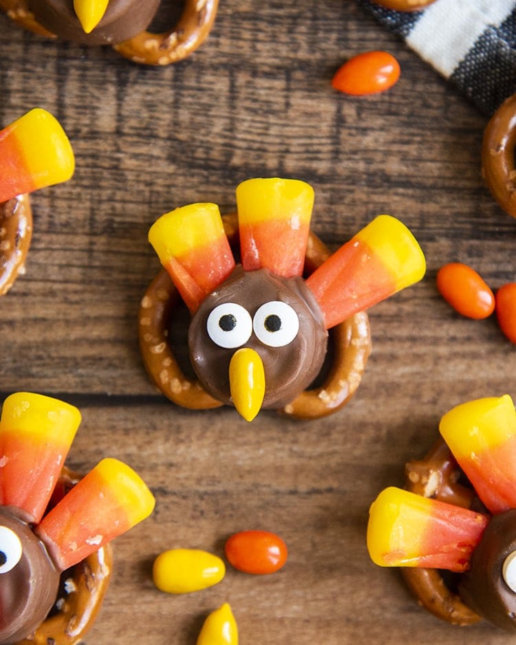 A pretzel topped with a rolo and decorated with candy corn, candy eyes, and a chocolate covered sunflower seed to make it look like a turkey.