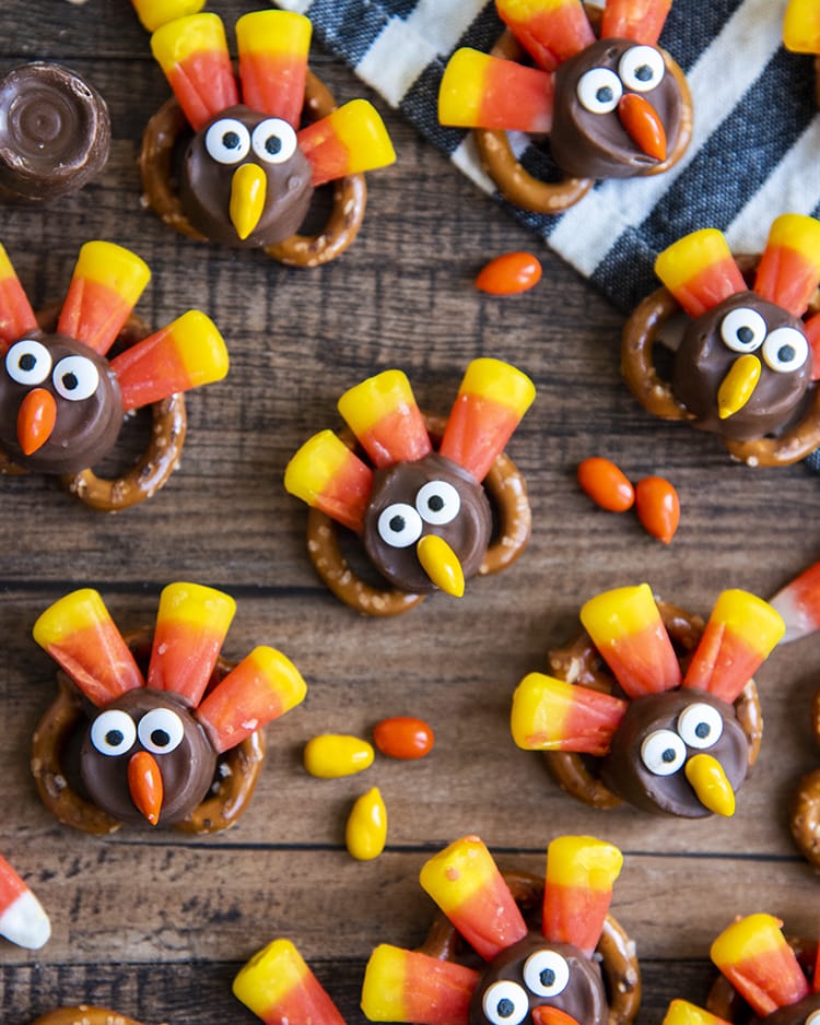 A bunch of turkey pretzel rolo treats on a wooden board.