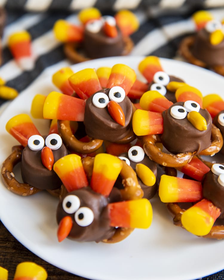 A close up of turkey pretzel rolo treats with a rolo and pretzel decorated with candy corn and candy eyes to look like turkeys.