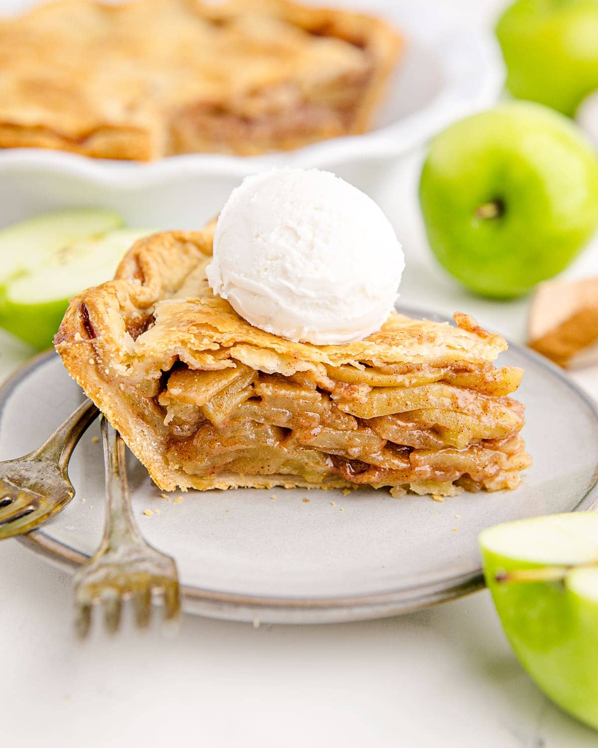 A piece of apple pie on a gray plate, served a la mode.