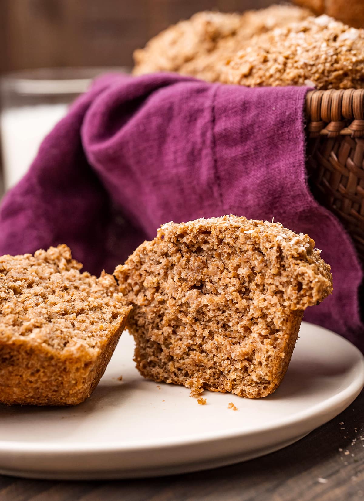 A bran muffin cut in half and put on a white plate.