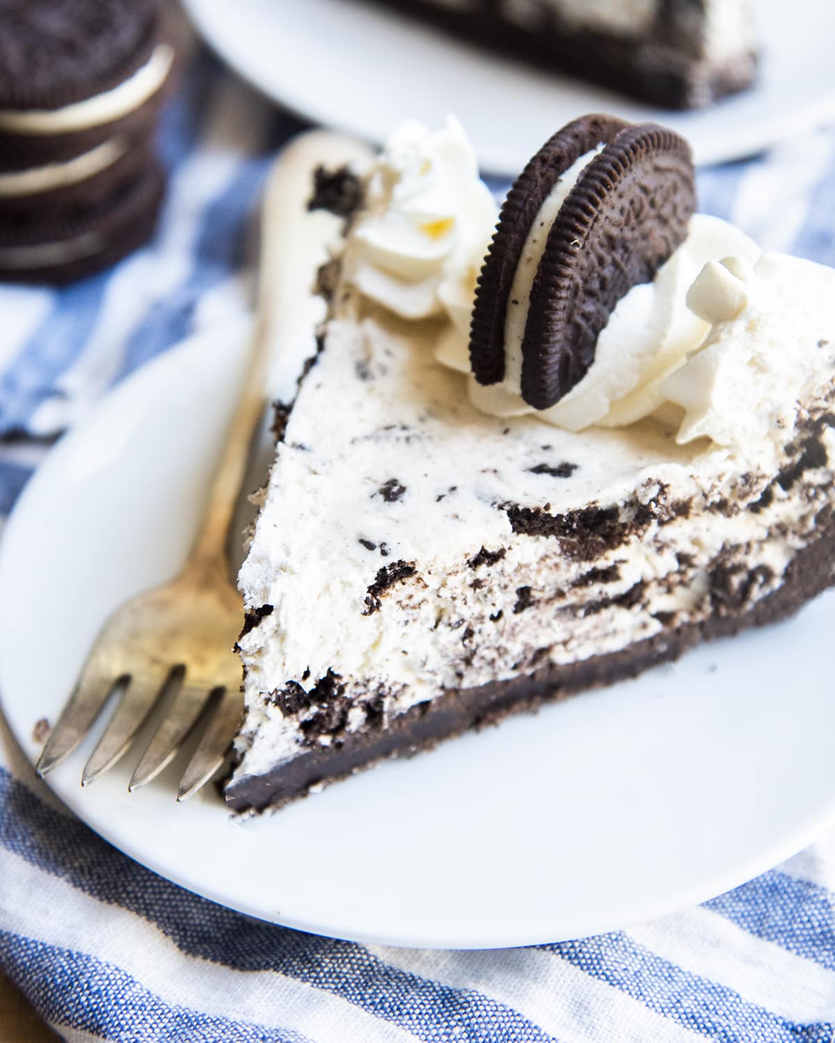 A slice of cookies and cream pie on a plate with a fork laying next to it.