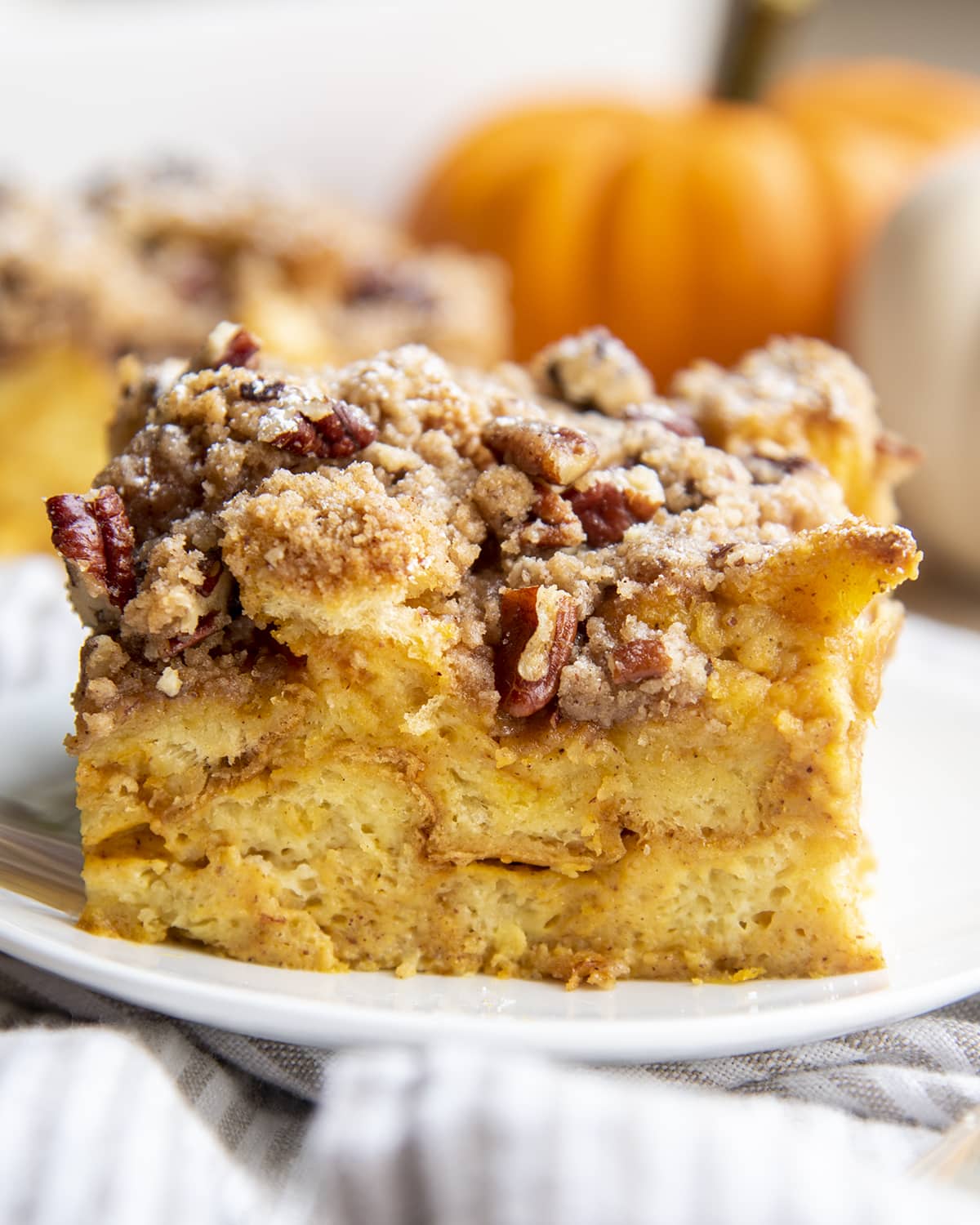 A piece of french toast casserole topped with a pecan cinnamon streusel topping.