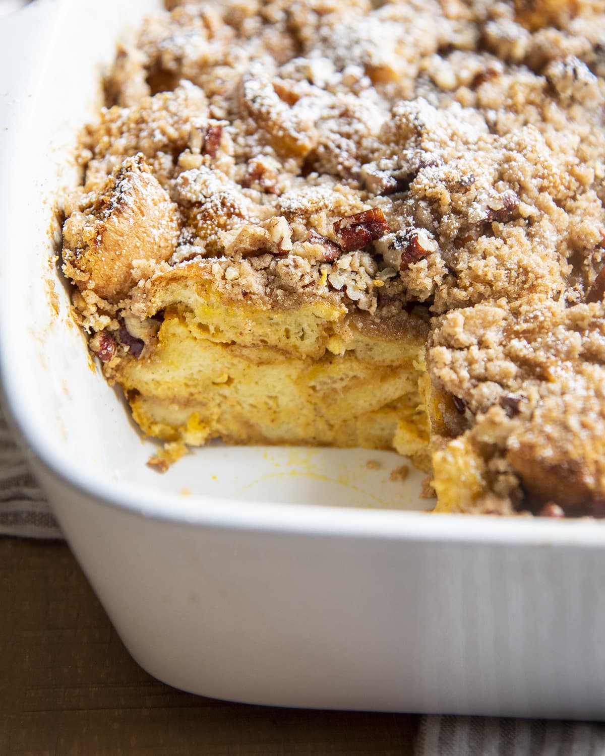 Pumpkin french toast in a baking pan with a piece removed from the pan.