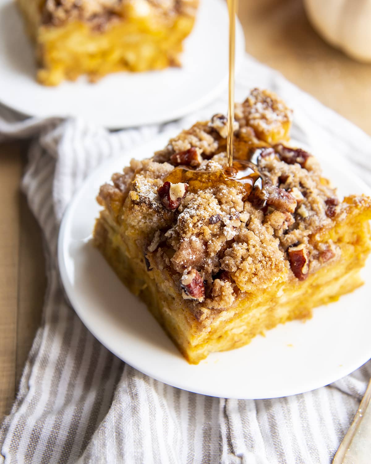 Syrup drizzling on a piece of pumpkin french toast casserole on a plate.