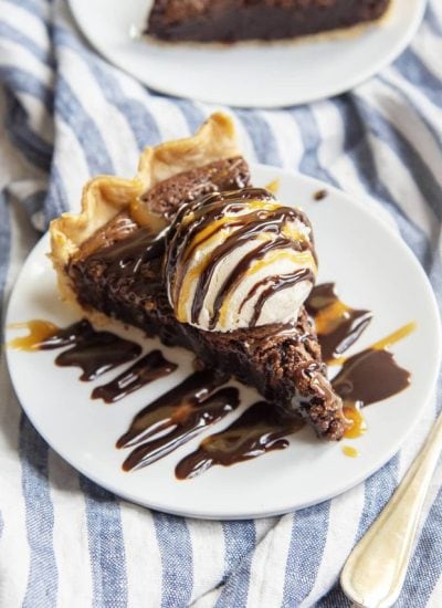 A slice of brownie pie with ice cream and caramel and chocolate on top.