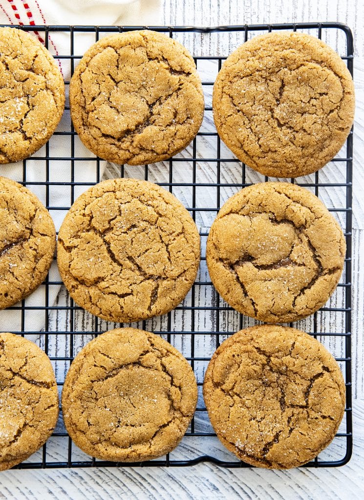 A cooling rack with ginger molasses crinkle cookies laying out on it.