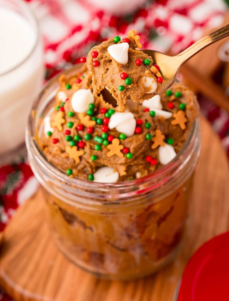 A spoonful of gingerbread edible cookie dough above a jar of cookie dough.