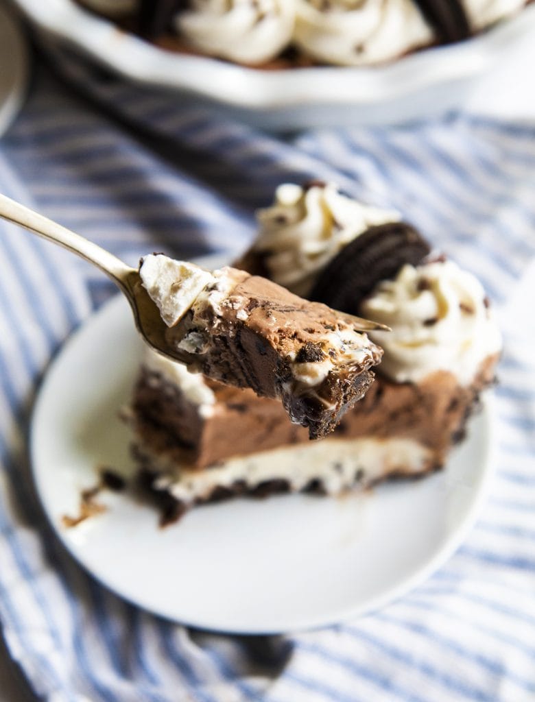 A spoonful of chocolate ice cream pie being held above a slice of the pie.