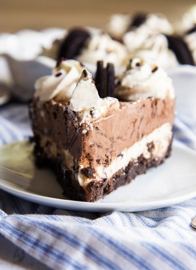 A slice of ice cream pie on a plate, topped with whipped cream and half an Oreo.