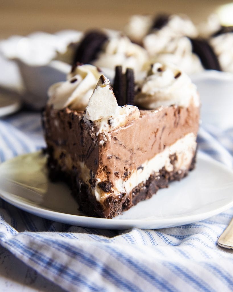 A slice of ice cream pie on a plate, topped with whipped cream and half an Oreo.