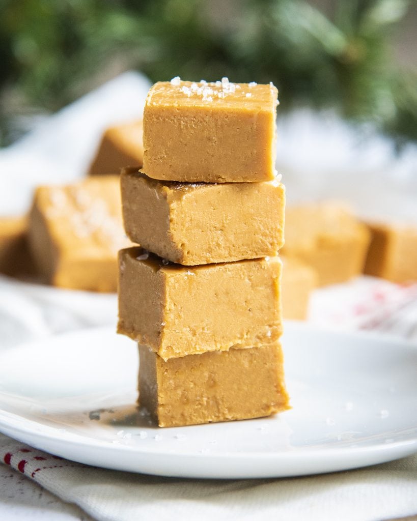A stack of four pieces of caramel fudge. The top piece is topped with coarse sea salt.