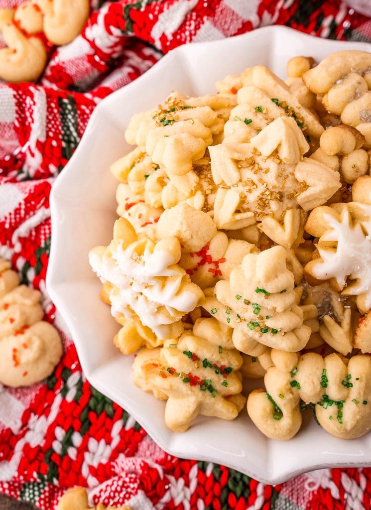 An overhead photo of a plate of spritz cookies, some are shaped like stars, some are trees, and some are snowflakes.