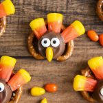 A square photo of pretzel rolo turkets with candy corn feathers.