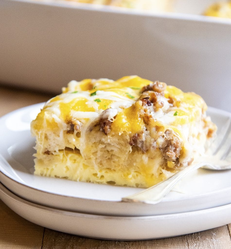 A piece of biscuit breakfast casserole showing a layer of egg, biscuit, sausage, and cheese.