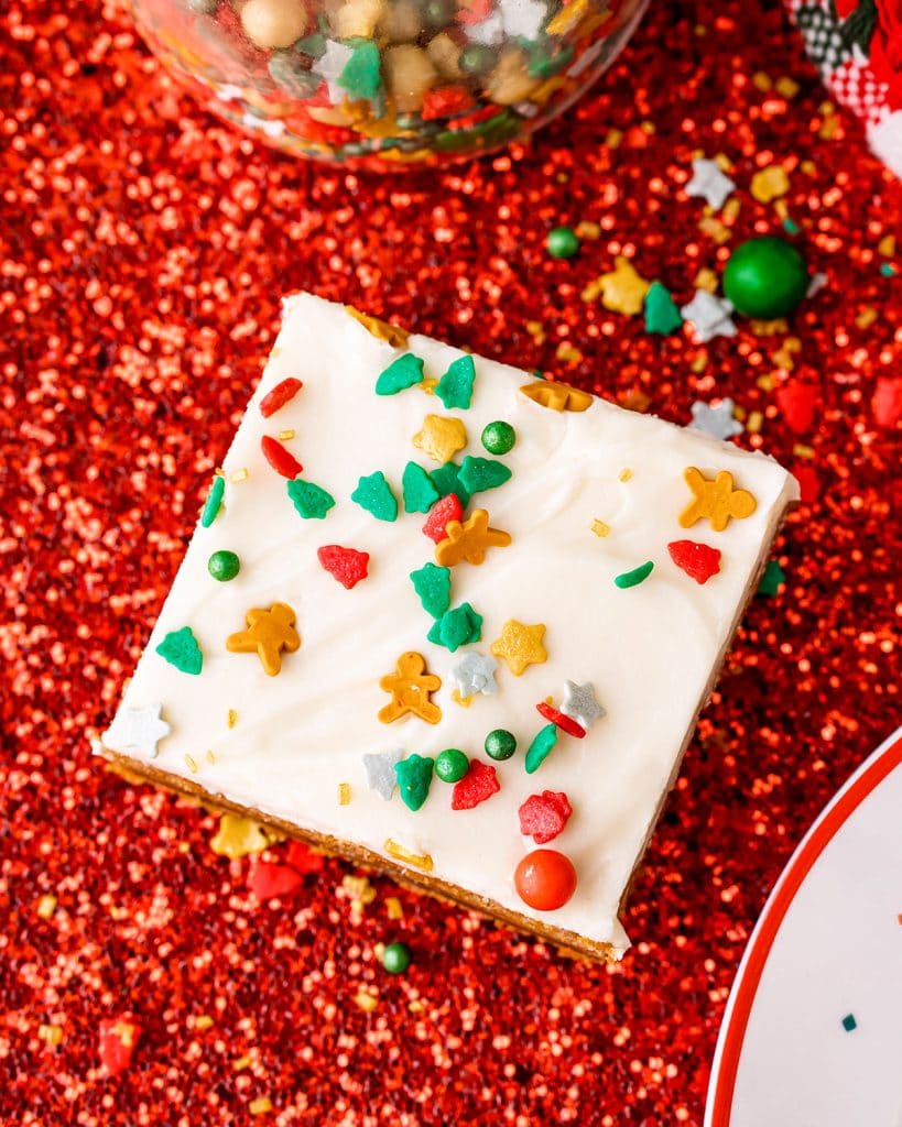 An overhead shot of a cookie bar on a white background. You can see the white frosting with sprinkles on top.