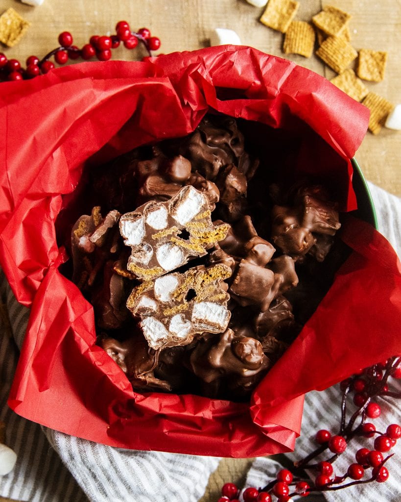 An overhead photo of s'mores clusters in a tin, one is cut in half to show the marshmallow and cereal middle.