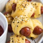 Pigs in a blanket on a plate, the image is topped with a text block for pinterest.
