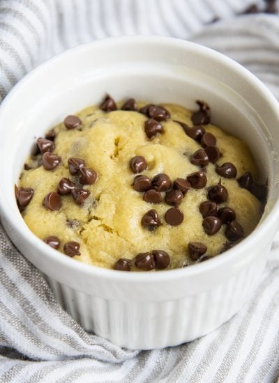 Chocolate chip cookie in a white ramekin, made in the microwave, and topped all over with mini chocolate chips.