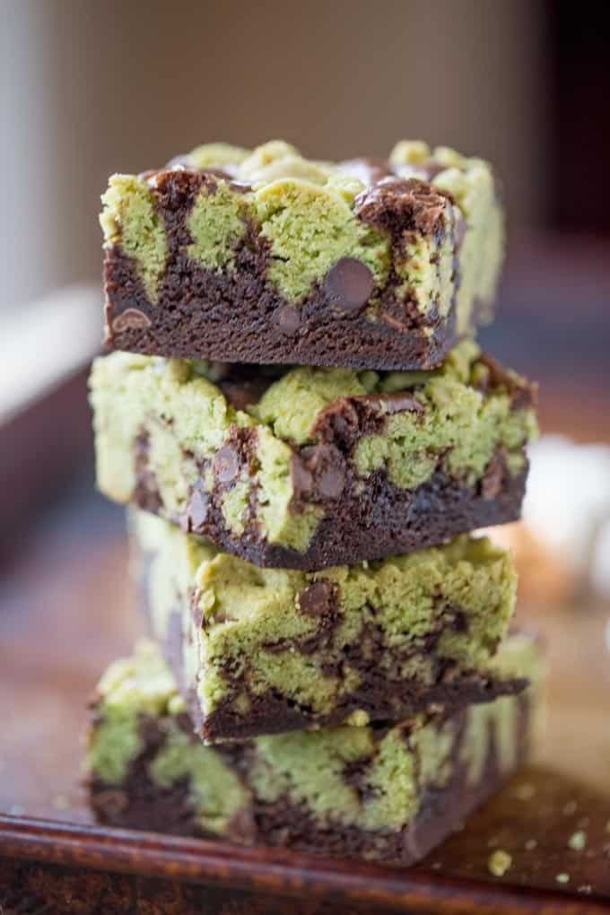 A stack of four mint chocolate chip brookies, with half brownie, half green mint chocolate chip cookie on each.