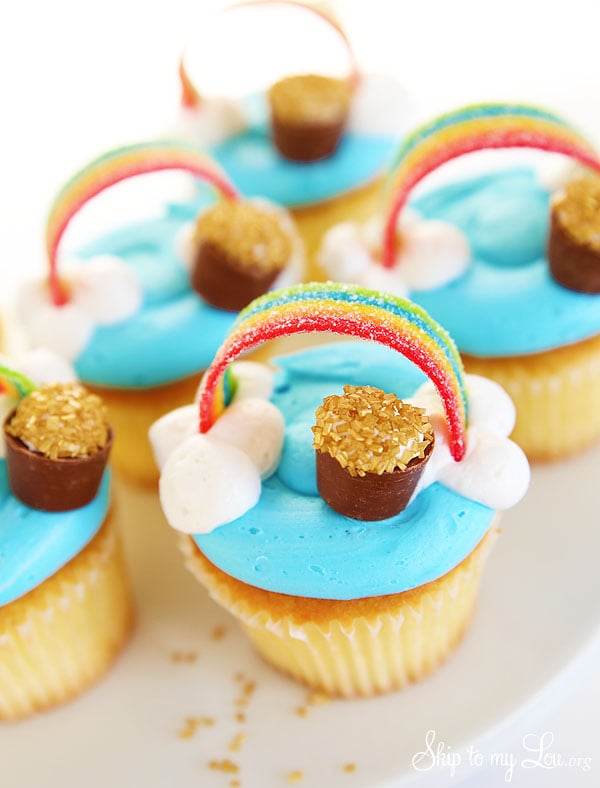 Cupcakes topped with blue frosting, rainbow candy and a candy pot of gold.