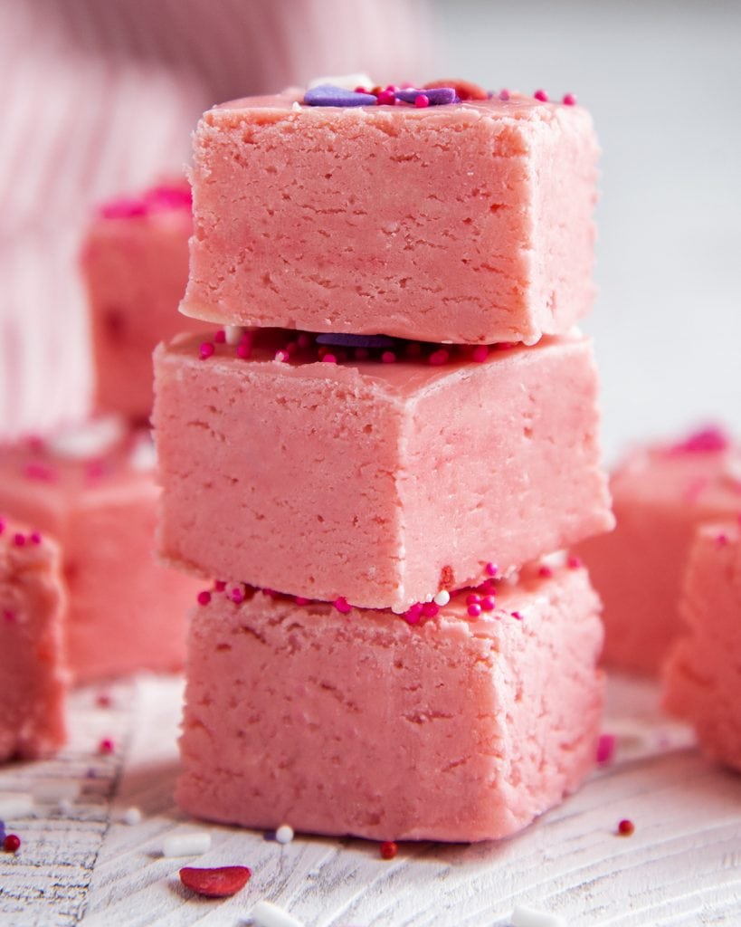A stack of 3 pieces of pink fudge.