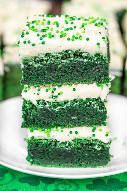 A stack of three green brownies on top of each other. They are each topped with a white frosting.