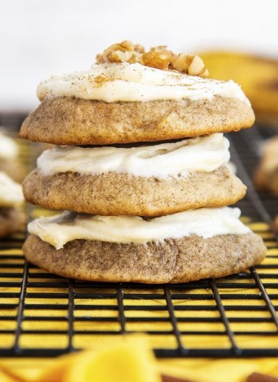 A stack of three banana cookies with cream cheese frosting on top.