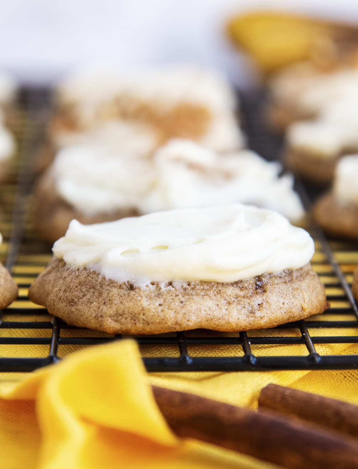 A banana cookie topped with cream cheese frosting on a cooling rack.