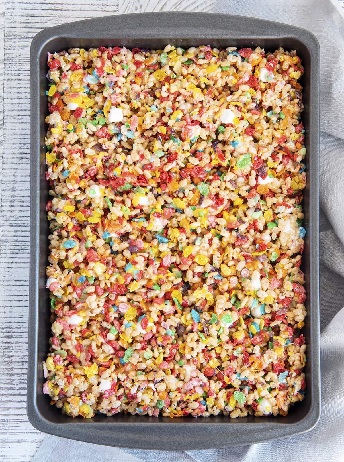 A baking pan full of fruity pebbles rice krispie treats.