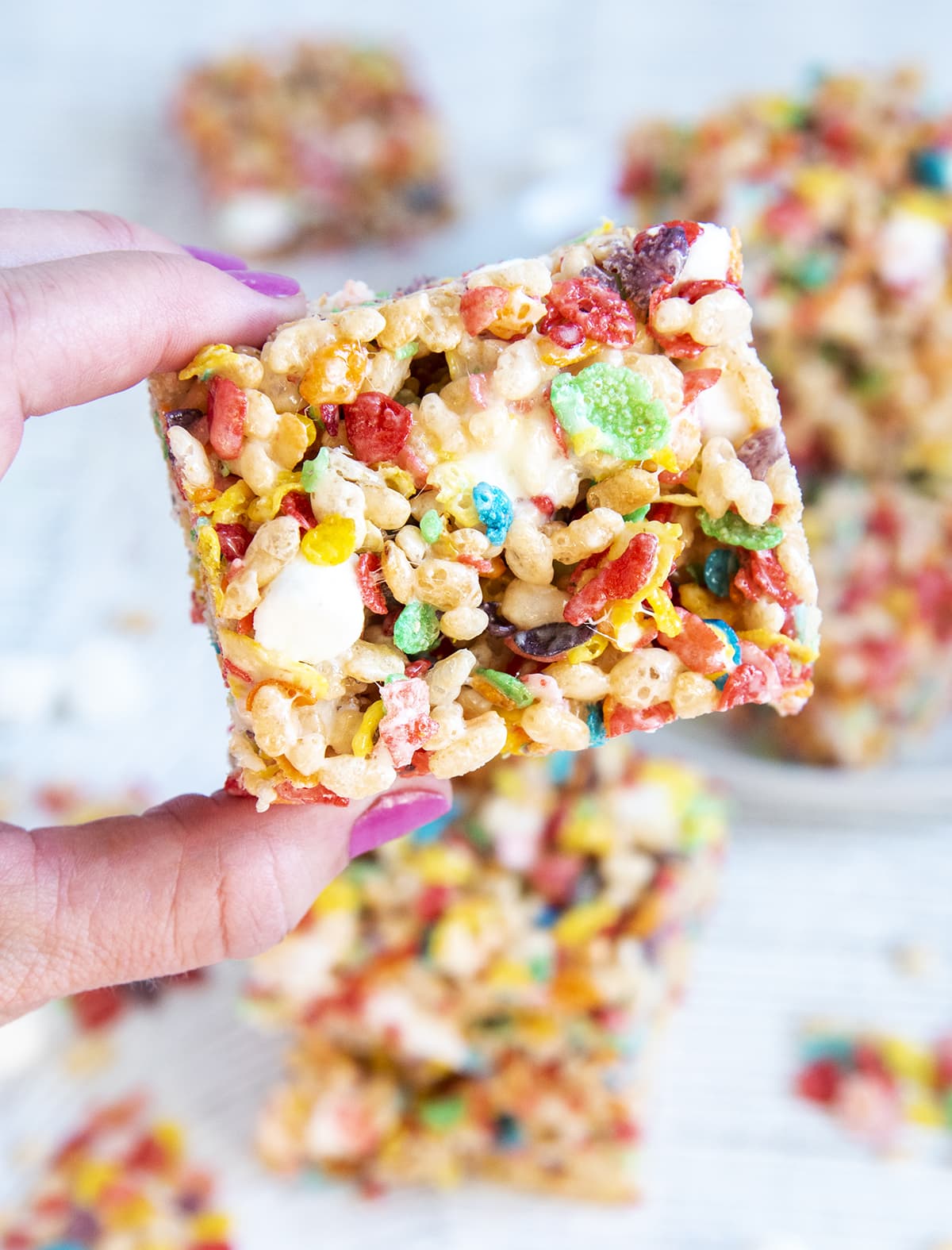 A hand holding a fruity pebbles rice crispy treat.