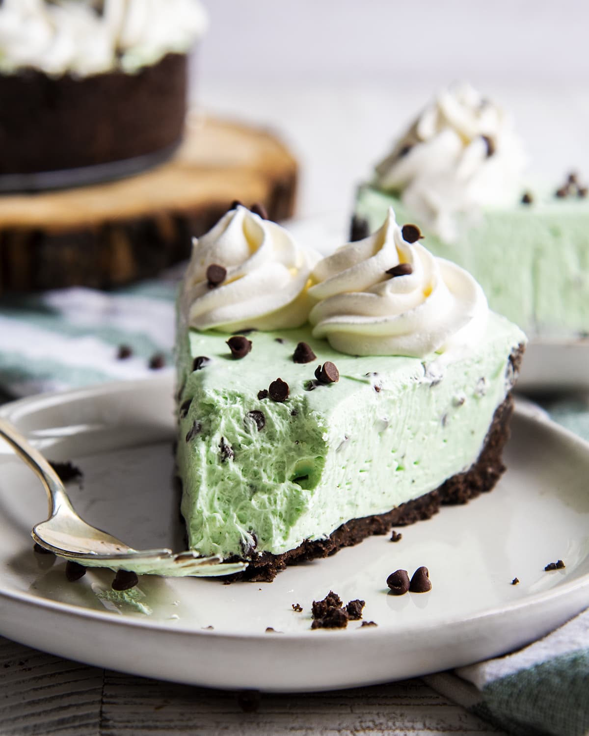 A piece of mint cheesecake with an oreo crust and a bite taken out of the front.
