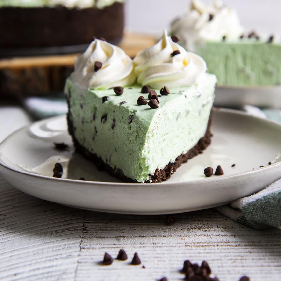 A square image of a slice of mint cheesecake shot straight on looking at the point of the slice.