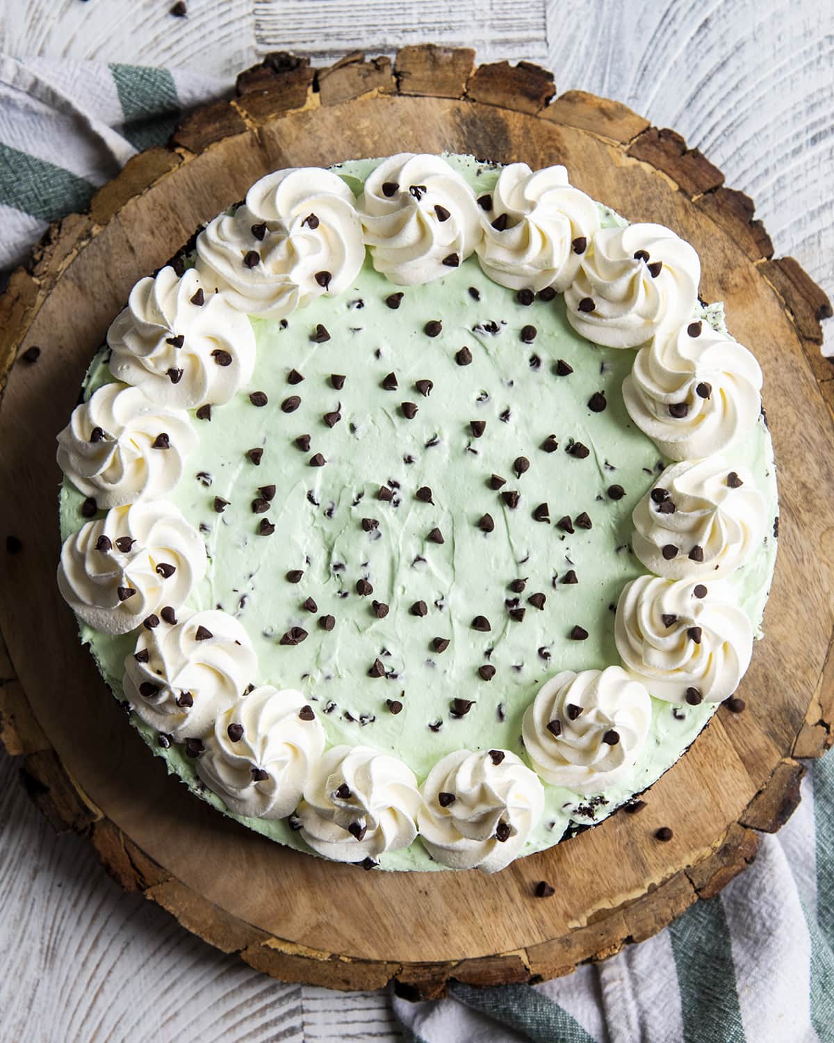 An above photo of a mint green cheesecake topped with mini chocolate chips, and whipped cream on the edges.