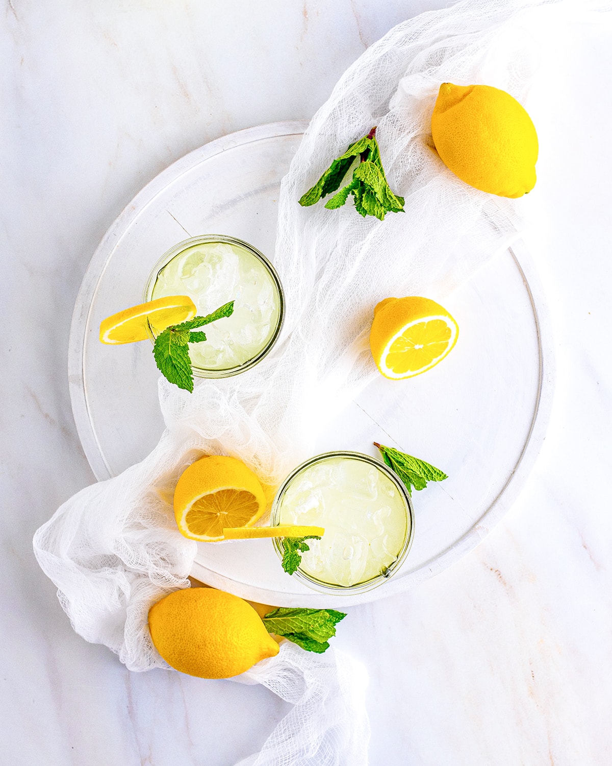 An overhead photo of two glasses of lemonade on a round platter.