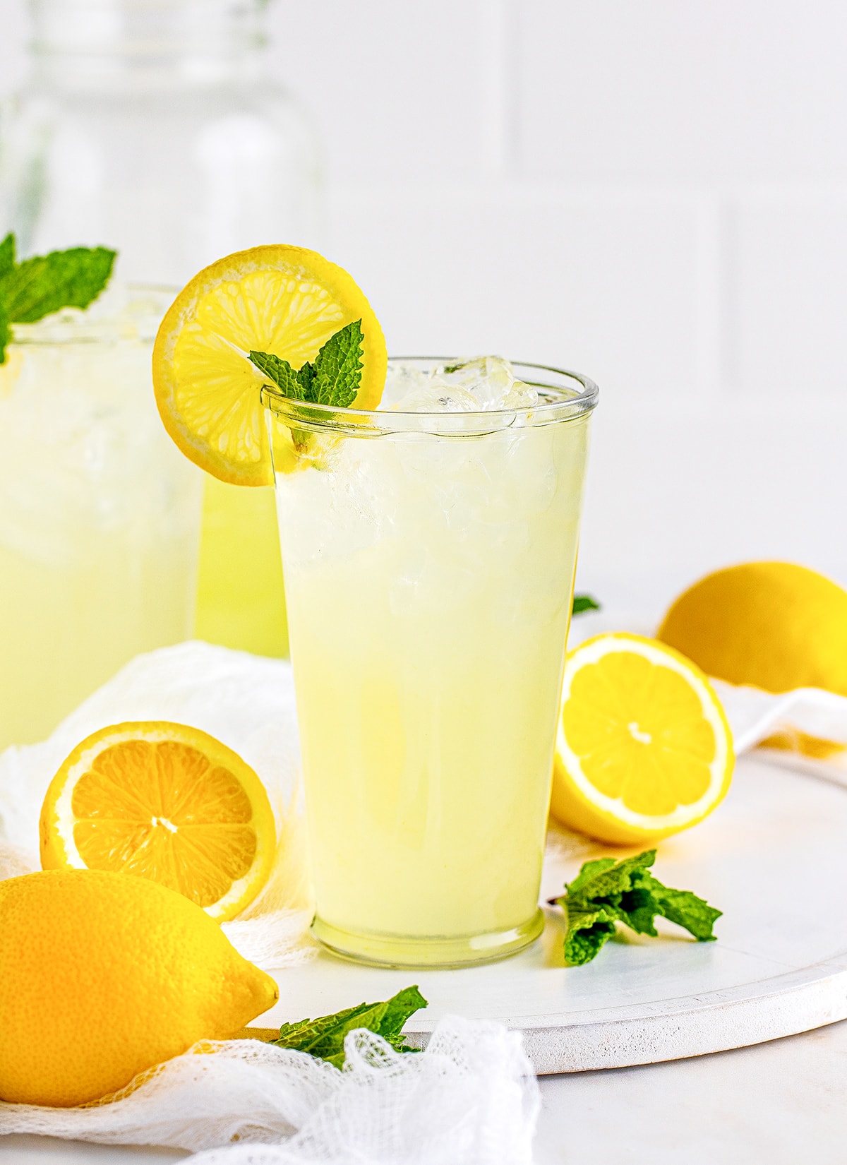 A glass of lemonade on a white platter.