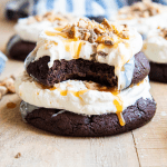 A close up of two Chocolate Heath Cake Cookies topped with a whipped cream cheese frosting and toffee pieces.