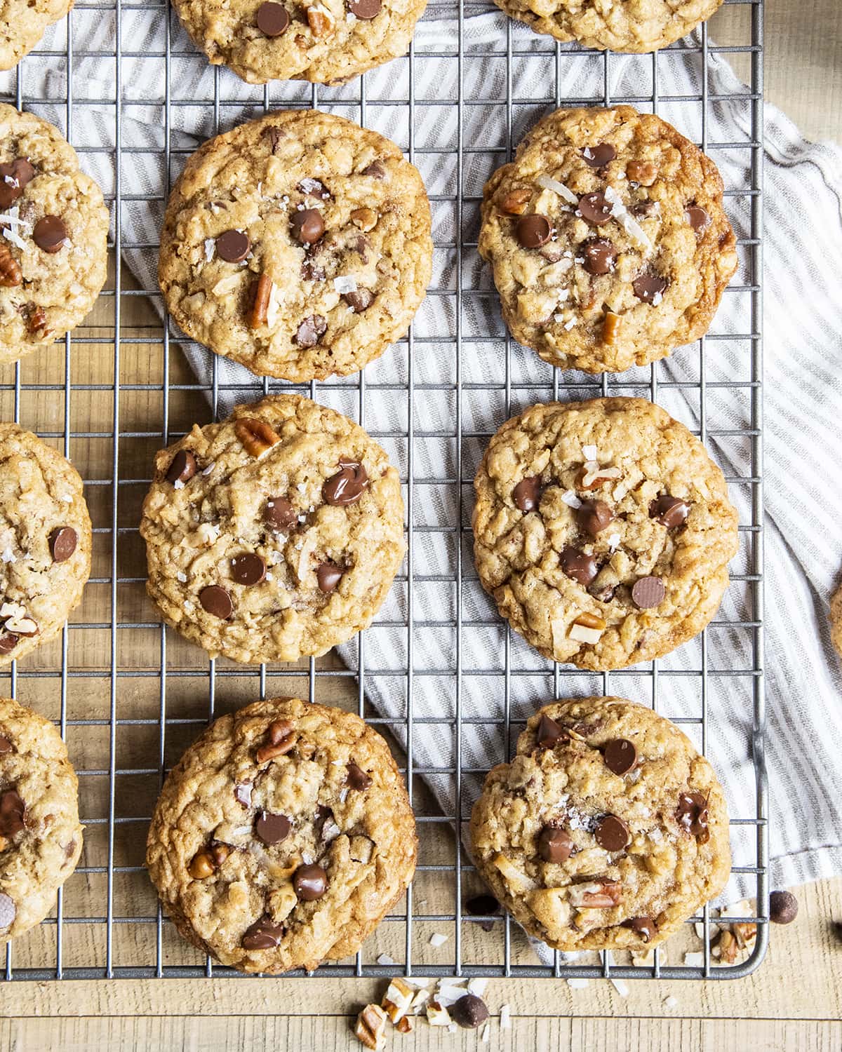 Cowboy cookies on a cooling rack topped with pecans and melted chocolate chips.