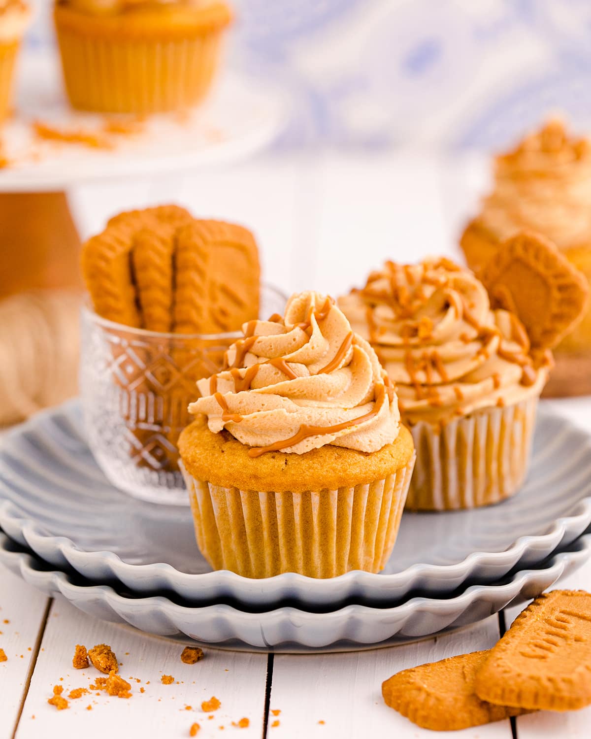 A plate topped with two Biscoff Cupcakes and a small bowl of Lotus Biscoff cookies.