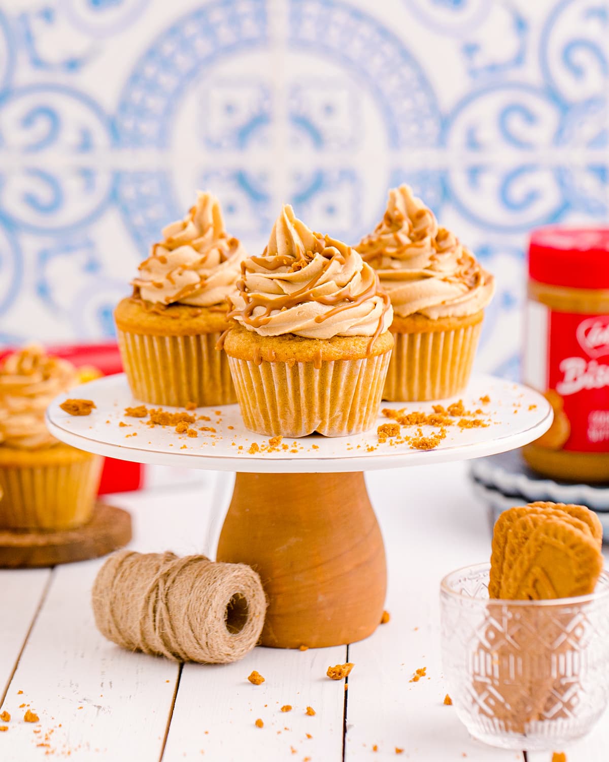 A cake stand topped with three cookie butter cupcakes with Biscoff Buttercream on top.