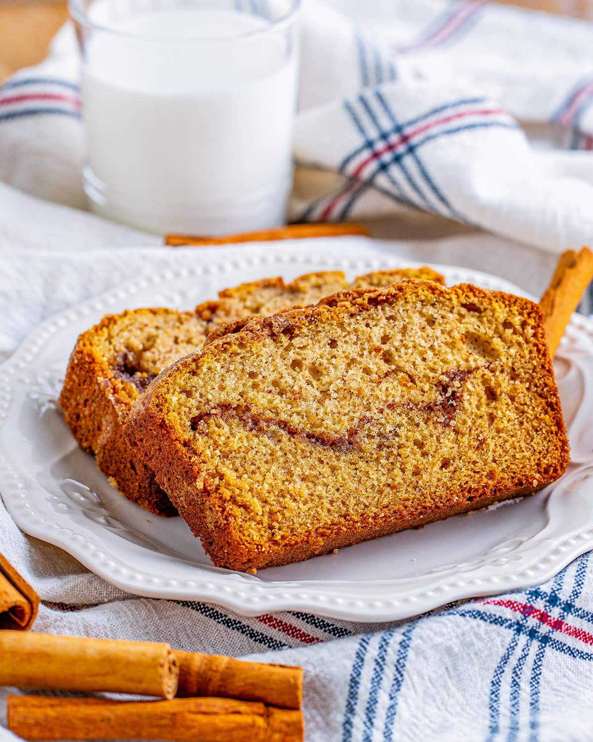 Two pieces of cinnamon quick bread laying on one another on a plate.