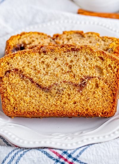 A close up of two pieces of cinnamon swirled quick bread on a white plate.